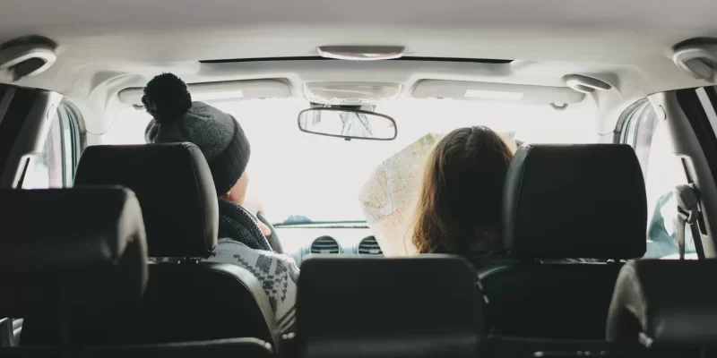 The couple of young man and woman in the car with paper map. Tra seguro-de-coche-tipo3